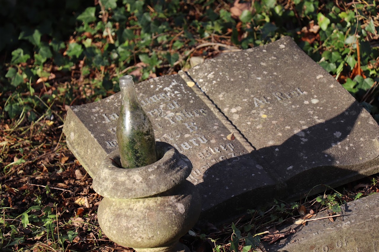 A stone grave marker and bottle among autumn leaves